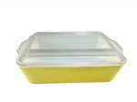 PYREX AMERICANO, um (1) pyrex retangular confeccionado em vidro opalinado na tonalidade branca com pintura amarela apresentando desgastes, tampa translucida com bicado na borda, medindo 7,5x25x18cm.