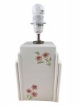 ABAJUR, um (1) abajur para uma lâmpada no estilo Art Deco, confeccionado em faiança vitrificada na tonalidade branca, decorado por flores e folhagens em policromia, apresenta sinais de craquele e oxidação na parte metálica superior, medindo 32cm de altura.