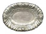METAL PRATEADO, uma (1) travessa oval confeccionada em metal espessurado a prata, ricamente cinzelada por florões, volutas, gomos torcidos e arabescos com recortes na borda, apoiada sobre 4 pés curvos, medindo 44,5x32,5cm.