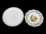 Hutschenreuther e Schumann, dois (2) pratos decorativos confeccionados em porcelana alemã na tonalidade branca, sendo: A) 1 feito para Munich Re (é uma das maiores companhias de resseguro do mundo em termos de prêmio subscrito), retratando ao centro DG Maximilianus Josephus Elector Bavariae com borda fileta em ouro, medindo 14,5cm e B) SCHUMANN,decorado por cena de época em policromia, borda em vazados com elementos florais e filetes em ouro, medindo 13cm.