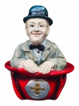 ESCULTURA, um (1) cofre confeccionado em faiança representando Stan Laurel ("O Magro") na Tigela com pintura policromada, medindo 17,5x13,5x13,5cm.