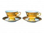 PORCELANAS, duas (2) xícaras de coleção para chá com seus respectivos pires confeccionadas em porcelana na tonalidade branca com vasta douração, decorada por elementos vegetalistas, interior em degradê na tonalidade azul e pínturas de cena galantes distintas em policromia, medindo 7x11,5x9,5cm.