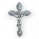 ARTE SACRA, um (1) crucifixo de parede confeccionado em metal espessurado a prata com cinzel de elementos florais em recortes ao centro reservando estrela com cristo em relevo, apresenta leve mossa na parte superior da cruz, medindo 17,5x11,5cm.