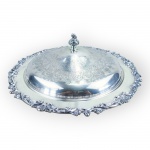 METAL PRATEADO, uma (1) petisqueira com tampa confeccionada em metal espessurado a prata da manufatura COMMUNITY, design Sheffield, cinzelado por elementos vegetalistas com borda em relevo e recortes, recipiente interno em vidro translucido com 5 divisórias, em excelente estado de conservação, medindo 13x36cm.