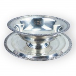 METAL PRATEADO, uma (1) saladeira com presentoir confeccionado em metal espessurado a prata da manufatura NATIONAL, cinzelado por guirlanda vegetalista nas bordas e base escalonada, apresentando leve percas na prateação, saladeira medindo 11x26,5cm e presentoir 31cm.
