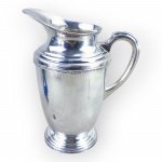 METAL PRATEADO, uma (1) jarra confeccionada em metal espessurado a prata da manufatura MERIDIONAL EPS, cinzelado por faixas decoradas por gomos torcidos e concheados, base escalonada e aparador de gelo vazado, medindo 23,5x19x9,5cm.