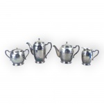 METAL PRATEADO, parte de serviço para chá/café confeccionado em metal espessurado a prata da manufatura REGIA, cinzelado por frisos horizontais em baixo relevo e alça por folhagens, apresentando falhas na prateação, sendo: A) 1 bule para chá, medindo 17x21x8cm, B) 1 bule para café, medindo 20x20x8cm, C) 1 açucareiro, medindo 13x17x8cm, leve mossa na tampa e D) 1 leiteira, medindo 12,5x12,5x6,5cm.