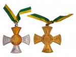 <b>MILITARIA</b>, duas (2) medalhas Ao Mérito, confeccionadas em metal dourado e bimetálico, em forma de cruz com inscrição Honra  Ao Mérito e centro ornado por coroa de louros. Ambas com fitas nas cores verde e amarela. Acompanham estojo original da marca Remi, forrado em cetim e assinado internamente Douração Garantida a Ouro 24K. Medindo 3,5x3,5cm.