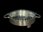 METAL PRATEADO, um (1) porta pirex redondo confeccionado em metal espessurado da manufatura WOLFF, corpo liso e pés recortados e alças vazadas, acompanha pirex da manufatura MARINEX, medindo 8,5x32x23cm. 1 PÉ QUEBRADO.