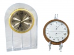 RELÓGIO e INSTRUMENTO, lote composto por duas (2) peças, sendo: A) um (1) relógio de mesa Quartz, com estrutura em acrílico transparente em formato arqueado, mostrador circular dourado com aro amarelo e algarismos romanos, não testado e sem garantia de funcionamento, medindo 18x12cm e B) um (1) termo-higrômetro analógico MOCO, com marcação de temperatura em C e umidade relativa, apoiada sobre placa redonda em madeira, aro metálico com sinais de oxidação, não testado e sem garantia de funcionamento, medindo 10cm.