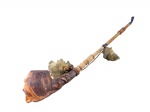 COLECIONISMO -  Um (1) cachimbo decorativo de estilo rústico/étnico, com fornilho em barro representando rosto masculino  trabalhado em tom marrom, ornamentação em relevo e haste longa em madeira torneada, acompanhado de cordões e aplicações em tecido , boquilha em material sintético na tonalidade preta , medida : 61 cm , possui bicados