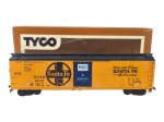 FERROMODELISMO, um (1) vagão fechado Tyco Santa Fe MTC, em material plástico, em escala para ferrorama, na cor amarela, com porta central azul, detalhes aplicados e inscrições laterais. Acompanha caixa original Tyco. Peça para composição ferroviária, apresentando sinais de uso, pequenas marcas e desgastes na embalagem, medindo 5,5x18x3,5cm.
