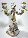 MEISSEN - MAGNÍFICO CANDELABRO EM PORCELANA DE MEISSEN, TRÊS LUMES  POLICROMIA RICAMENTE ORNADO COM FIGURAS ESCULPIDAS REPRESENTANDO CENA PASTORAL E CUPIDO MARCA DA MANUFATURA NO VERSO DA BASE. MEDIDAS: 26 X 15 CM