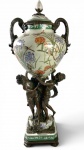 GRANDE ÂNFORA ESTILO ROCAILE EM PORCELANA POLICROMADA FLORAL NO BOJO CENTRAL E SUSTENTADA POR FIGURAS DE MULHERES EM BRONZE PATINADO. PERFEITO ESTADO. MEDIDAS: 56 CM DE ALT.