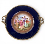 DELICADO CENTRO DE MESA EM PORCELANA TCHECA  AZUL COBALTO COM CENA  BORDAS COM DECORAÇÃO DOURADA, DESGASTE NA DOURAÇÃO, GUARNIÇÃO EM BRONZE. MEDIDAS: 20 CM
