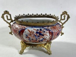 IMARI-JAPAN - JARDINIÈRE EM PORCELANA IMARI COM MONTAGEM ARMAÇÃO EM BRONZE ORMULU- CURIOSIDADES:  A PRÁTICA FRANCESA DE MONTAR PORELANAS JAPONESAS  IMARI EM ORMULU ERA AMPLAMNETE PRATICADO NO PERÍODO NAPOLEÃO III NO MERCADO EUROPEU. MEDIDAS: 14 X 21 X 13 CM . NECESSITA FIXAÇÃO DOS COMPONENTES