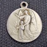 Brasil / Internacional, antiga medalha/pingente religiosa em metal prateado dedicada ao "SANTO ANJO DA GUARDA". Anverso apresentando o Anjo da Guarda em relevo guiando e protegendo uma criança. Reverso ostentando figura masculina junto a uma árvore. Peça dotada de passador para corrente, apresentando pátina e desgastes naturais pelo uso que atestam sua antiguidade. Belíssimo item devocional e colecionável!