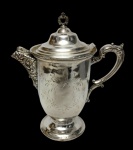 RICHFIELD PLATE Co.  Antiga chocolateira americana em metal prateado, estilo vitoriano. Corpo de linhas elegantes, assentado sobre base circular, ricamente ornamentado com gravações de ramos, folhas e arabescos, apresentando bico vertedor e alça em exuberante decoração em relevo de influência rococó. Tampa de encaixe com pegador vazado de desenho ornamental. Medidas: 30 x 27 x15 cm.