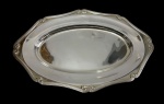 Fracalanza  Antiga e imponente travessa em metal espessurado a prata, de formato ovalado com extremidades facetadas, borda cinzelada em delicados relevos de inspiração rococó. Medidas: 44,5 x 28,5 cm.