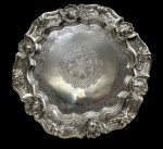 Antiga salva em metal espessurado a prata, no estilo D. João V, de formato circular, borda recortada e ricamente cinzelada com conchas, volutas e motivos vegetalistas em relevo. Centro finamente lavrado com medalhão de inspiração geométrica e ornamental. Medidas: 35 cm.