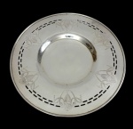 Antigo prato de aparador / presentoir em metal espessurado a prata, de formato circular, borda vazada com frisos geométricos e delicadamente gravada com guirlandas, liras e motivos neoclássicos. Centro liso em suave rebaixo. Medidas: 2,5 x 23,5 cm.