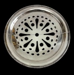 Antigo descanso para travessas regulável em metal espessurado a prata, de formato circular, com centro vazado em desenho geométrico e borda contornada por delicado friso. Sistema articulado que permite ajuste do diâmetro conforme a travessa a ser apoiada. Apresenta ausência de um parafuso no mecanismo de regulagem. Medidas: 30 cm de diâmetro (fechado) e 38 cm (aberto).