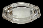 Christofle, França. Bandeja em metal espessurado a prata, de formato oval, com centro liso e borda recortada de contorno moldurado. Marca da manufatura gravada na borda. Medidas: 27 x 17,5 cm.