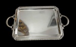 Wolff. Imponente bandeja em metal espessurado a prata 90, de formato retangular, com centro liso, borda moldurada com friso em padrão entrelaçado e alças laterais vazadas ornamentadas por folhagens em relevo. Marca da manufatura gravada. Medidas: 54 x 32 x 2 cm.