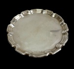 Sheffield. Antiga bandeja em metal espessurado a prata, de formato circular, com centro liso levemente martelado e borda recortada em contorno moldurado. Marca da manufatura gravada. Medidas: 20,5 cm.