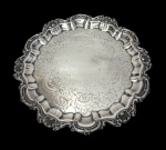 Antiga bandeja em metal espessurado a prata, de estilo Rococó, com centro ricamente gravado por arabescos e motivos florais, aba moldurada com gomos e borda recortada ornamentada em relevo por conchas, volutas e cartelas. Apoiada sobre três pés. Medidas: 2,5 x 26,5 cm.