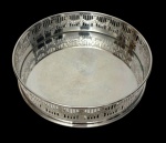 Wolff. Antigo porta-garrafa em metal espessurado a prata, de formato circular, com corpo vazado, ornamentado por guirlandas em relevo e bordas lisas. Apresenta desgaste no banho de prata. Medidas: 3,5  15 cm.