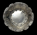 Antigo centro de mesa em metal espessurado a prata, em estilo Rococó, de formato circular com borda recortada, ricamente ornamentada em relevo com volutas, flores e folhagens, centro liso. Apresenta leves desgaste no banho de prata. Medidas: 17 cm de diâmetro.
