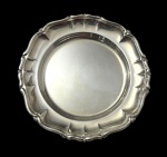 Antiga bandeja em metal espessurado a prata, de formato circular, com borda moldurada em contorno recortado de inspiração Luís XV e centro liso. Apresenta desgaste no banho de prata. Medidas: 14,5 cm de diâmetro.