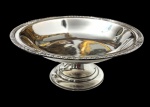 Antiga e imponente fruteira em metal espessurado a prata, com corpo circular elevado sobre pedestal, borda moldurada e ornamentada em relevo de inspiração Luís XVI, centro liso. Apresenta leve desgaste no banho de prata. Medidas: 13 x 32 cm.