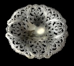 Meridional. Antiga fruteira em metal espessurado a prata, de formato circular, com borda vazada e ricamente cinzelada com volutas, flores e folhagens em estilo Rococó, centro liso. Manufatura marcada. Apresenta desgaste no banho de prata. Medidas: 4 x 19 cm.