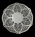 Mappin & Webb. Prince's Plate, London & Sheffield. Antiga bandeja em metal espessurado a prata, de formato circular, com corpo totalmente vazado em ricos arabescos e folhagens em estilo Rococó, centro liso com monograma gravado. Manufatura marcada. Medidas: 25 cm de diâmetro.
