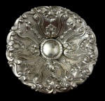 Antiga fruteira em metal espessurado a prata, de formato circular elevada sobre pedestal, ricamente cinzelada em estilo Rococó, com borda recortada, ornamentada por conchas, volutas e folhagens em relevo. Apresenta desgastes. Medidas: 7 x 20,5 cm.