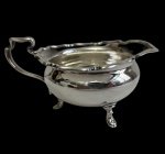 Antiga molheira em metal espessurado a prata, manufatura inglesa (England), com corpo bojudo, borda recortada, bico vertedor, alça vazada e três pés de apoio. Medidas: 6,5 x 13,5 x 9 cm.