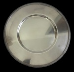 CHRISTOFLE  Antiga bandeja circular em metal espessurado a prata, de renomada manufatura francesa, com aba lisa e centro rebaixado, de linhas clássicas e elegantes. Manufatura gravada na peça. Medidas: 30,5 cm de diâmetro.