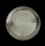 Antiga e imponente bandeja redonda em metal espessurado a prata, marcada na base, com borda vazada, corpo ricamente cinzelado com decoração floral e centro gravado em arabescos. Apoiada sobre quatro pés recortados. Medidas: 3 x 35,5 cm.