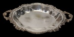Sheffield. Antiga e imponente fruteira em metal espessurado a prata, marcada na base. Corpo de contorno recortado, centro moldurado com aba ondulada, borda ricamente ornamentada em relevo com motivos florais e concheados, apresentando alças vazadas integradas ao corpo.  Medidas: 6 x 41 x 24 cm.