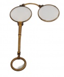 Antigo lupa de metal dourado, com duas lentes articuladas e cabo ornamentado em relevo, apresentando argola terminal para manuseio. Medidas: 13 x 9,5 cm.