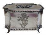 Sheffield. Antigo porta-joias em metal espessurado a prata, de formato retangular, apoiado sobre quatro pés, com tampa ornamentada em relevo por brasão e laterais gravadas com motivos heráldicos. Bordas molduradas com frisos em relevo. Medidas: 10,5 x 16,5 x 12,5 cm. Apresenta desgastes.