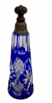 Antigo perfumeiro de cristal Double Azul, na tonalidade azul e translúcido, corpo ricamente lapidado com motivos geométricos e estrela na base, tampa com montagem em metal. Apresenta pequeno bicado na base. Medidas: 18,5 x 6 cm