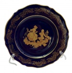 Limoges, France. Prato decorativo em porcelana, na tonalidade azul-cobalto, ricamente ornamentada com frisos em ouro e cena galante em reserva central. Manufatura no verso. Medidas: 18,5 cm.