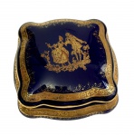 Limoges, France. Antiga caixa com tampa em porcelana, na tonalidade azul-cobalto, ricamente ornamentada com frisos em ouro e cena galante em reserva central. Manufatura no verso. Medidas: 9,5 x 4,5 x 9,5 cm.