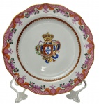 Antigo prato de coleção em porcelana portuguesa, reprodução oficial do Serviço D. Pedro III, Século XVIII, com brasão da Coroa Portuguesa ao centro, borda recortada ricamente ornamentada com motivos florais policromados e filetes em ouro. Instituto dos Museus e da Conservação (IMC) / Palácio Nacional de Queluz. Medidas: 20 cm de diâmetro.