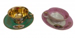 Duas xícaras para café com seus respectivos pires, em porcelana, sendo uma na tonalidade verde-esmeralda alemã e outra rosa japonesa, decoradas com reservas representando cenas galantes, ornamentos florais e rica douração. Interior parcialmente dourado, alças e bordas filetadas a ouro. Manufaturas no verso.