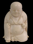 Antiga pequena escultura em marfim, representando Buda sorridente em posição sentada, com vestes esculpidas em relevo e colar de contas. Medidas: 6,7 x 4,7 x 2 cm.