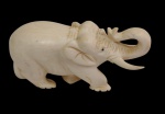 Antigo elefante em marfim, esculpido, representado com tromba elevada e presas entalhadas. Rica modelagem com detalhes nas orelhas, patas e adereços sobre a cabeça. Medidas: 9 x 4,6 cm.
